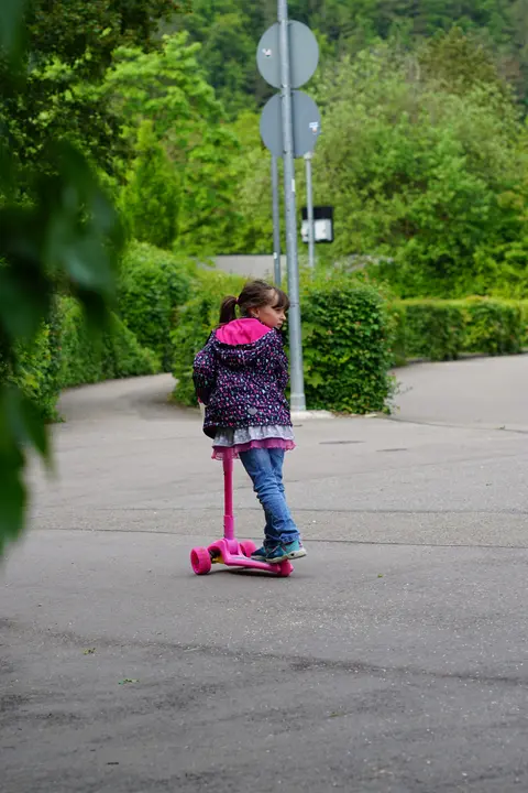 Kind fährt mit einem pinken Roller